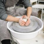 Close-up of a potter's hands shaping clay on a pottery wheel, showcasing craftsmanship.