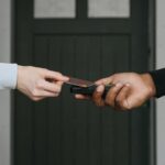 Close-up of hands exchanging credit card for contactless payment, emphasizing cashless transactions.